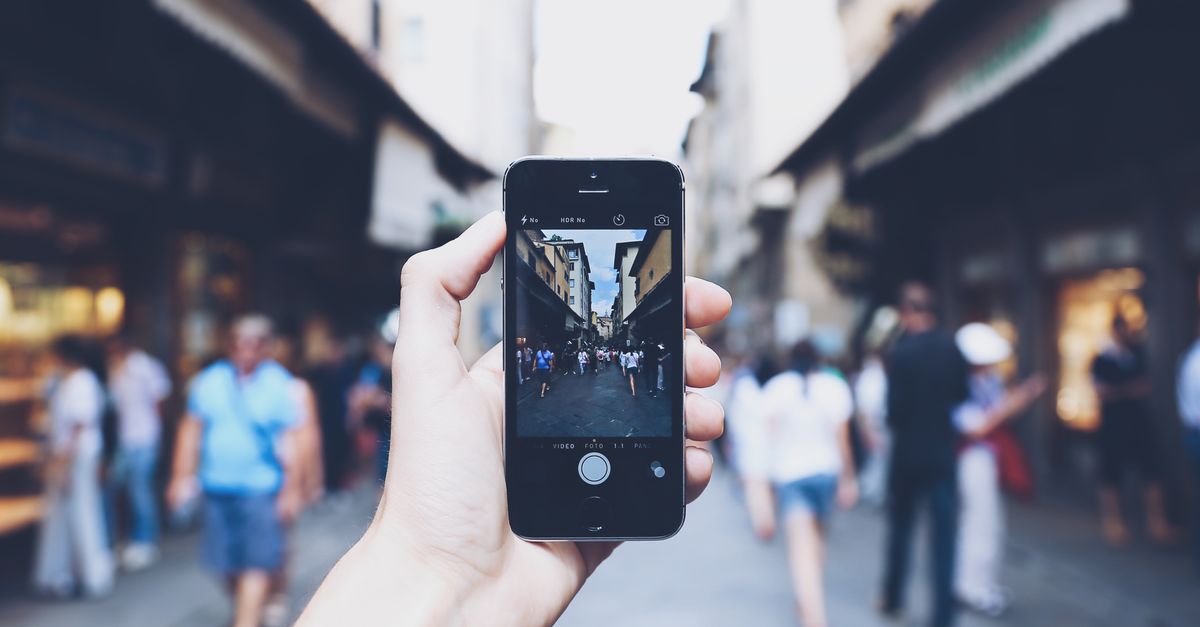 A first-person view of a smartphone being used to navigate a busy city street.