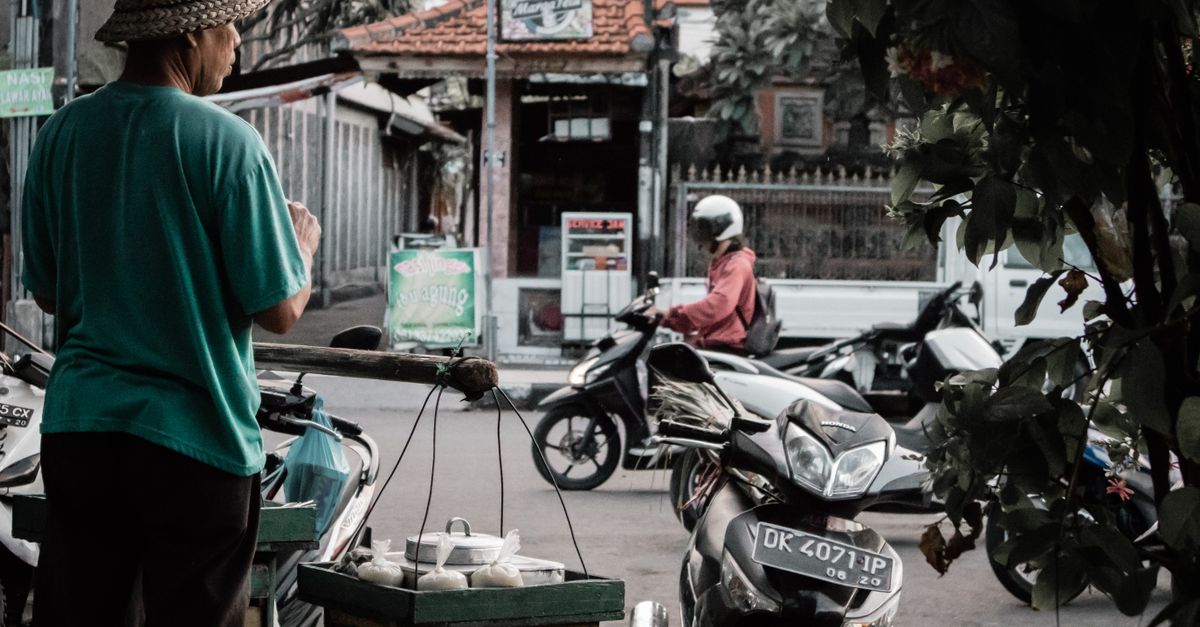 Street vendor in Bali selling goods to passing motorcyclists