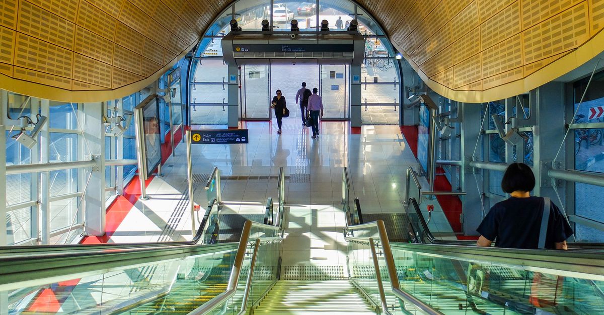 Interior view of a modern Dubai Metro station with passengers on escalators