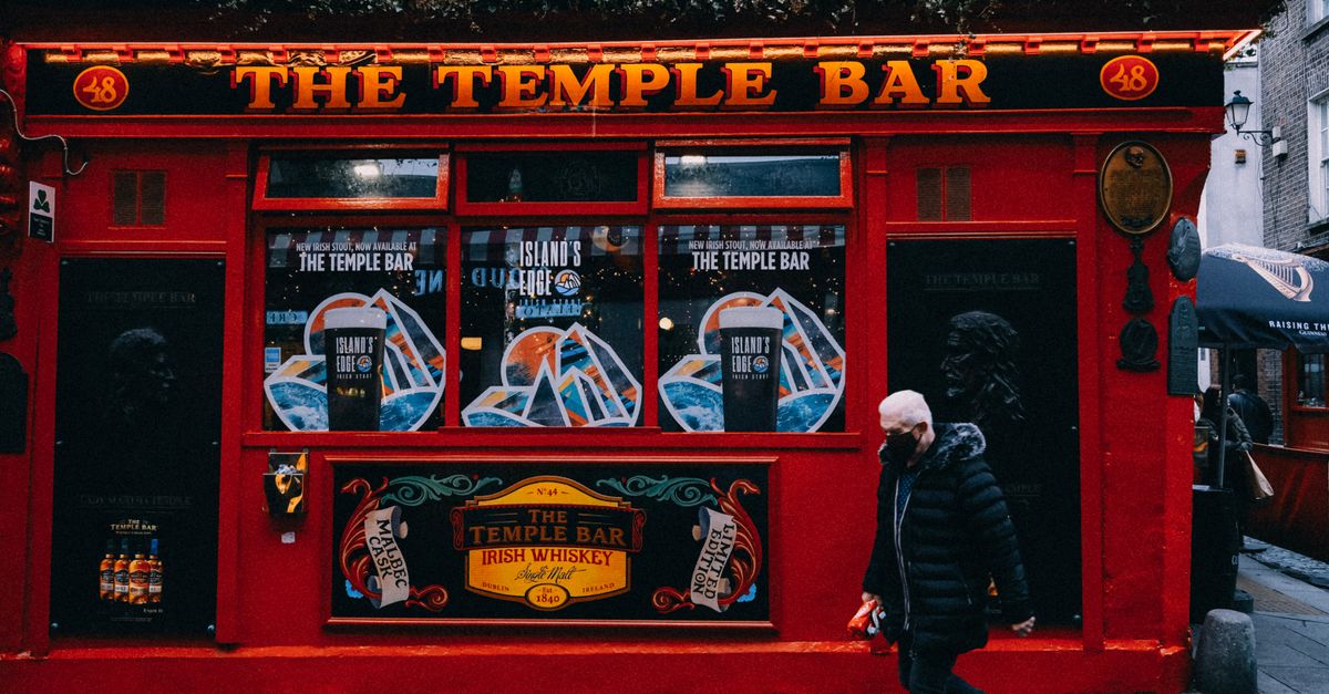 The iconic red facade of The Temple Bar in Dublin on a busy street.